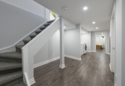 A view beneath a finished basement staircase, showcasing plenty of storage space.