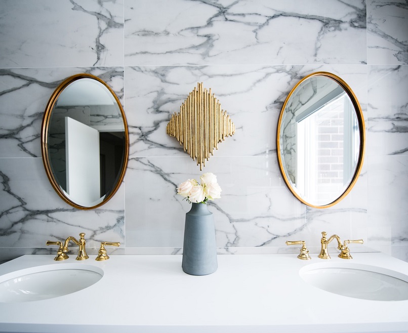 marbled tile bathroom walls with ceramic counter tops and gold detailing